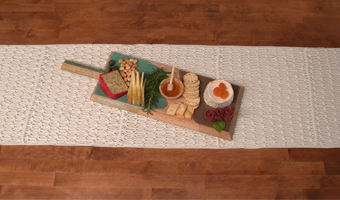 Various food items served on a wooden charcuterie board decorated with epoxy resins in two colors.